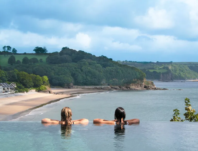Two ladies in an infinity pool overlooking the coast.