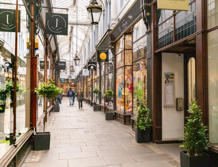 Shoppers walking down a Victorian arcade in a city centre.