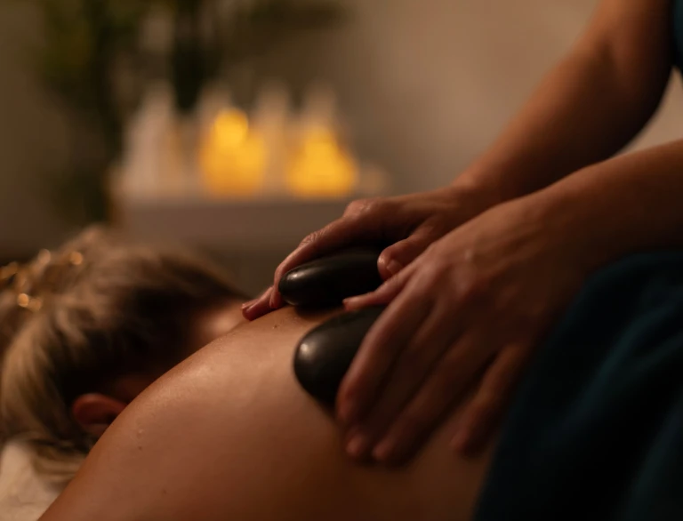 A lady lying face down and enjoying a stone massage at a hotel spa.