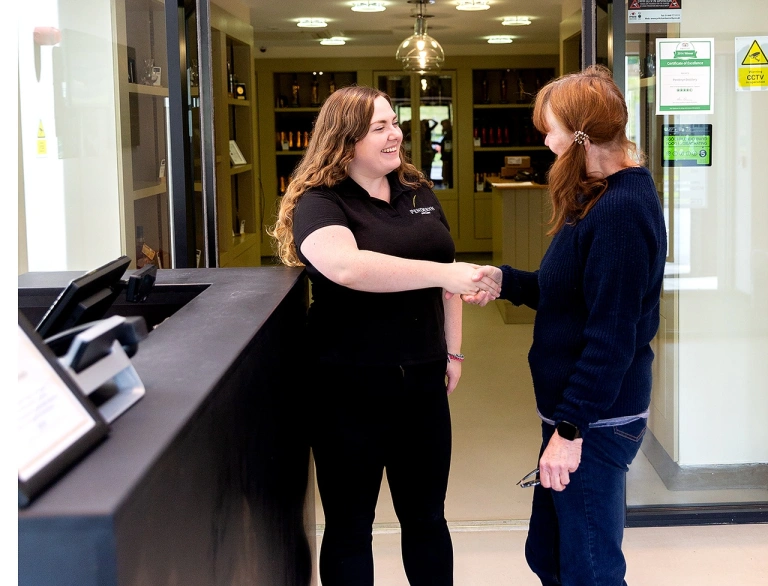 A tour guide welcoming a guest at their distillery.