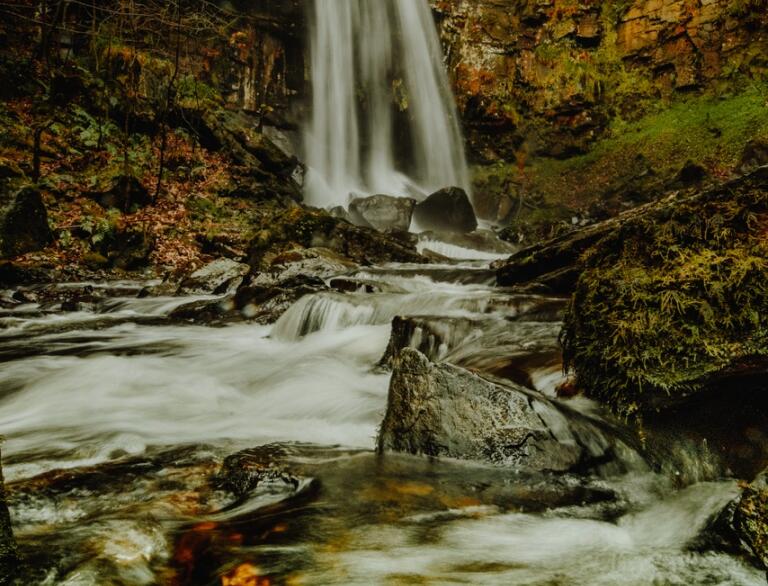 a rushing waterfall in autumnal woodlands