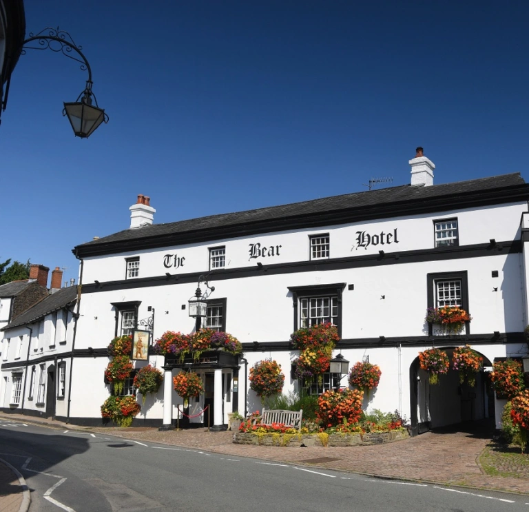 A traditional hotel adorned with flower baskets and window boxes in a town.