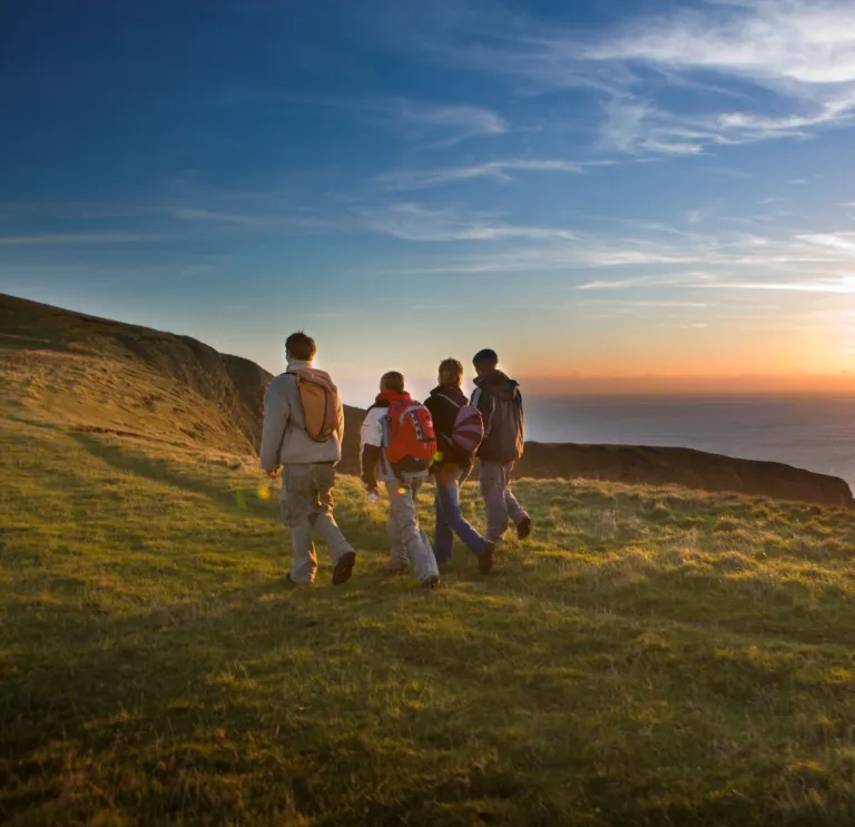 Four walkers enjoying the sunset along the Glamorgan Heritage Coast.