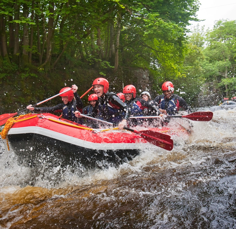 A group of people whitewater rafting down a river.