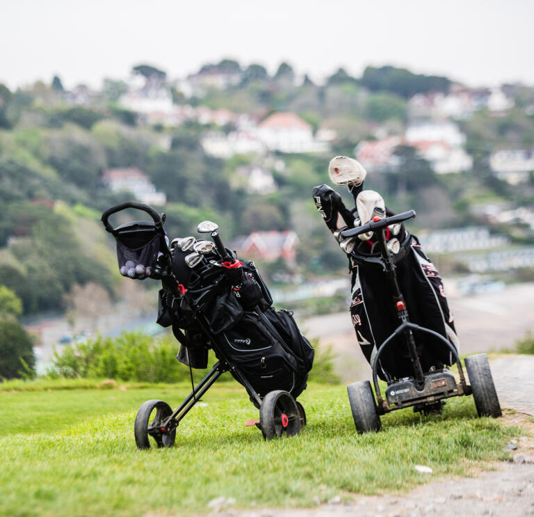 Golfing trolleys with Langland Bay in the background.