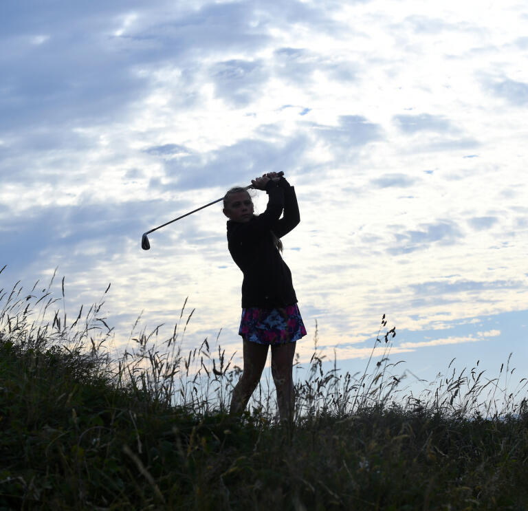 Silouette of a lady golfer taking a swing at Pyle and Kenfig Golf Club.