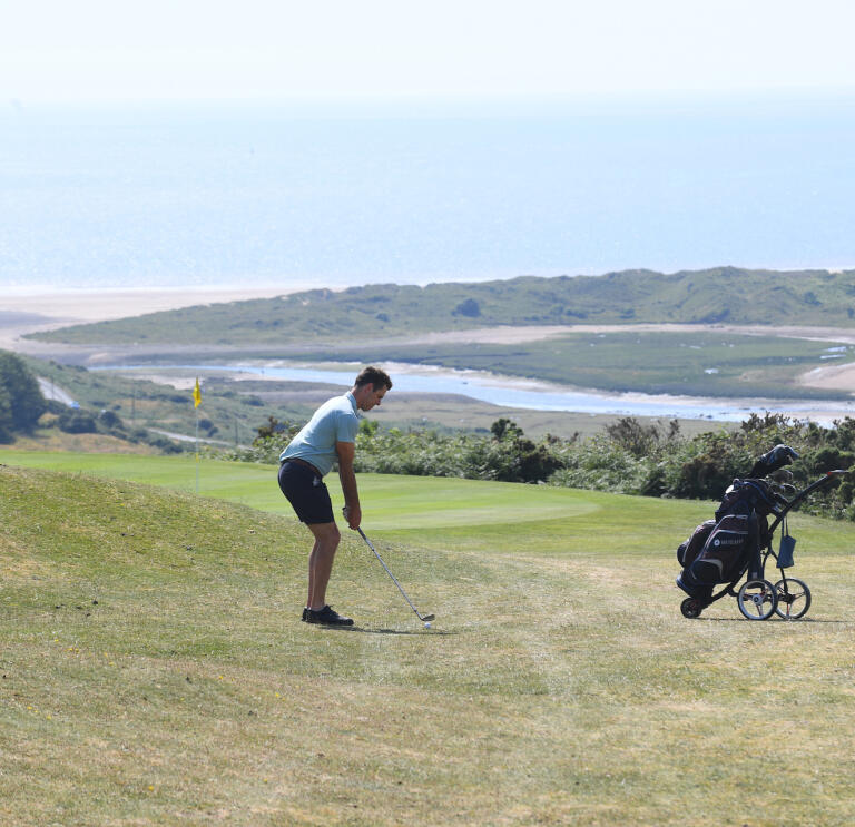 Golfer preparing to chip the ball onto the green at Southerndown Golf Club.
