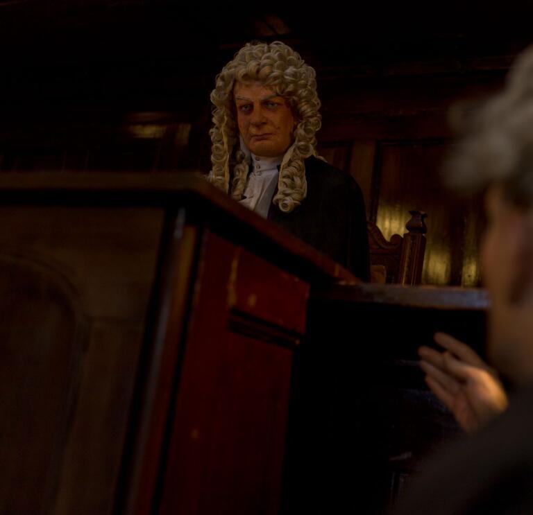 A waxwork judge presiding over a courtroom.