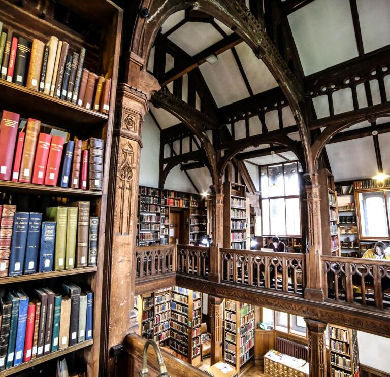 A library taken from a balcony showing shelves of books and an ornate roofspace.