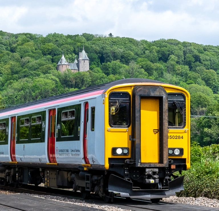 A train passing a fairytale castle on a hill.