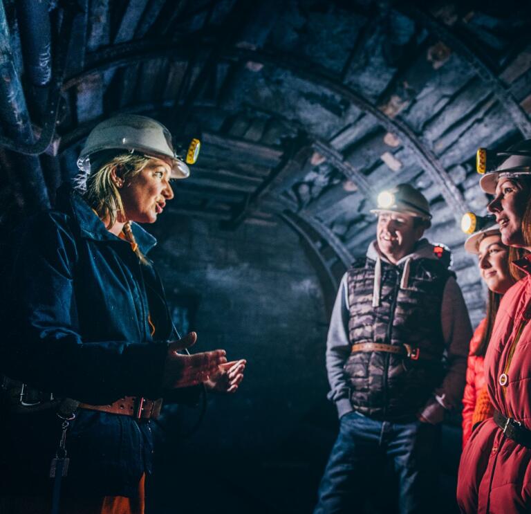 A tour guide talking to visitors in a former underground mine.