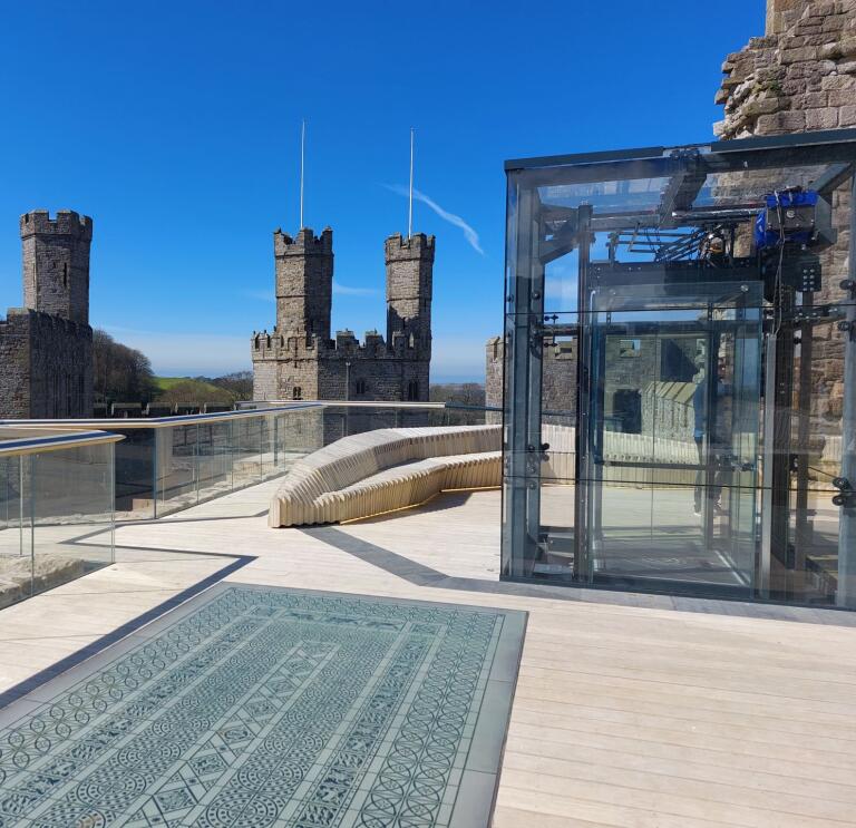 A viewing platform and glass lift inside a castle.