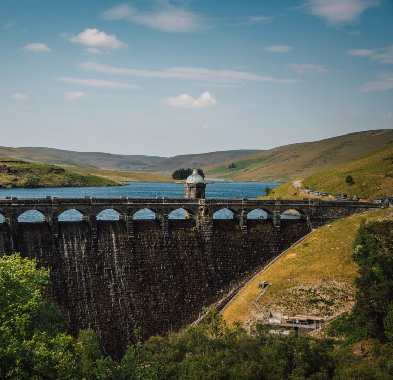 Aerial shot of a dam and a reservoir with mountainous scenery.