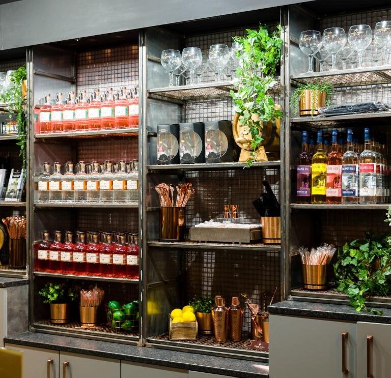 Shelves containing bottles of gin, glasses and shakers.