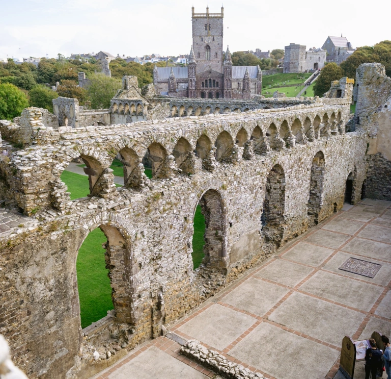 Ruins of a bishop's palace with a cathedral in the background.