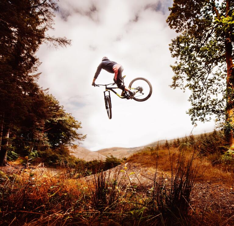 A mountain biker performing a dramatic jump in a forest