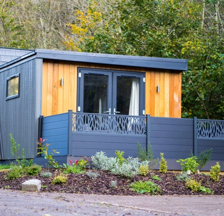 A blue wooden four berth lodge in a forest park.