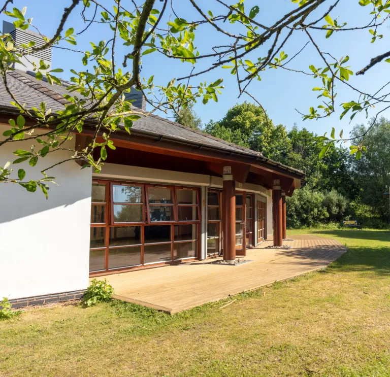 External shot of a conservatory surrounded by green trees.