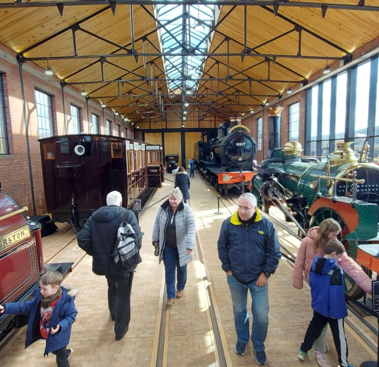 People viewing historic steam locomotives at museum.