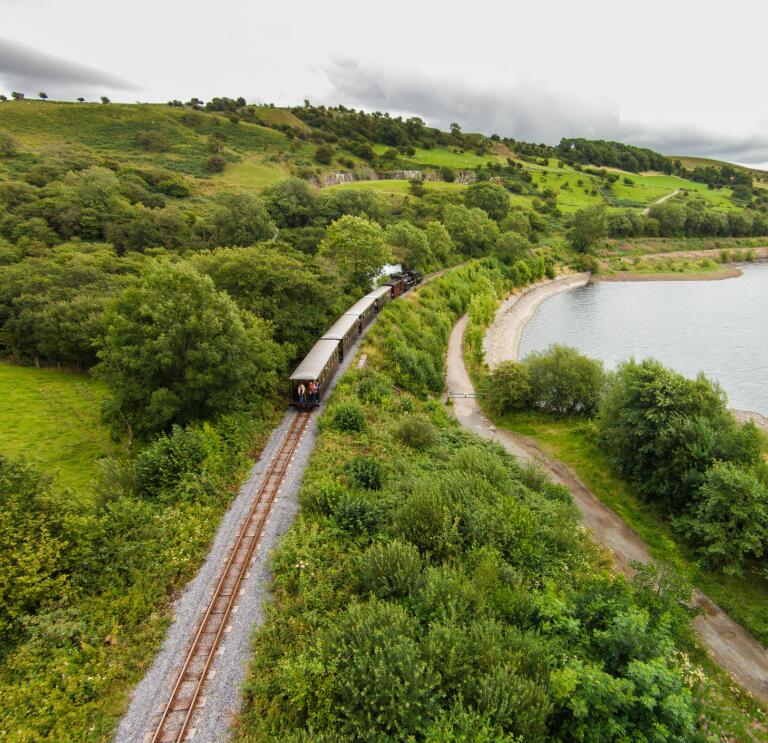 A train in the countryside passing a reservoir.