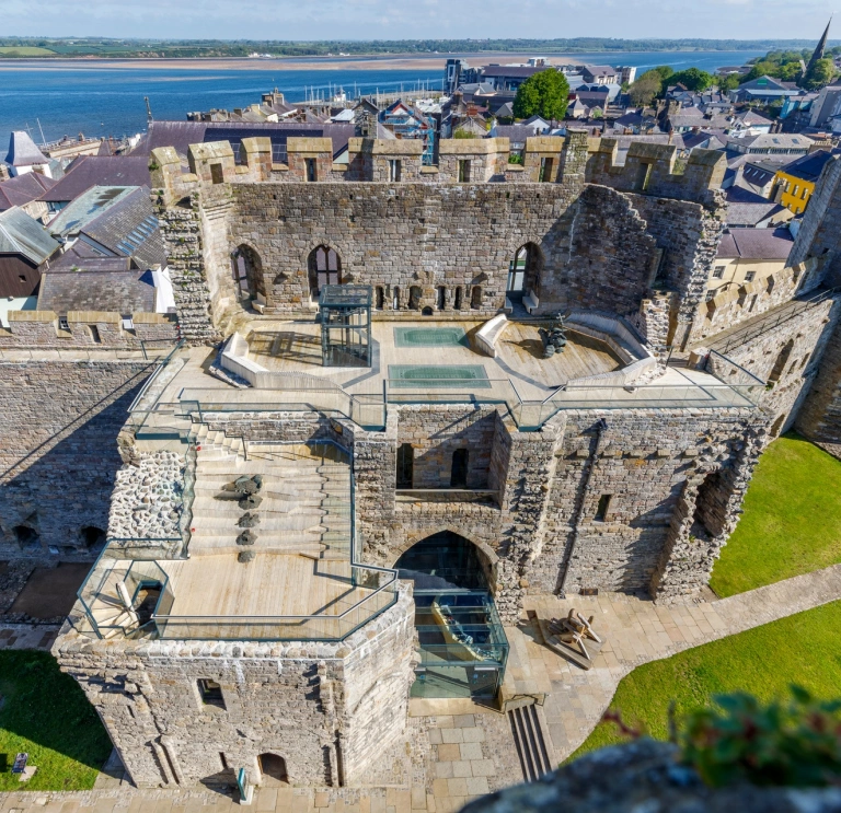 Aerial shot of a castle with the coast beyond.