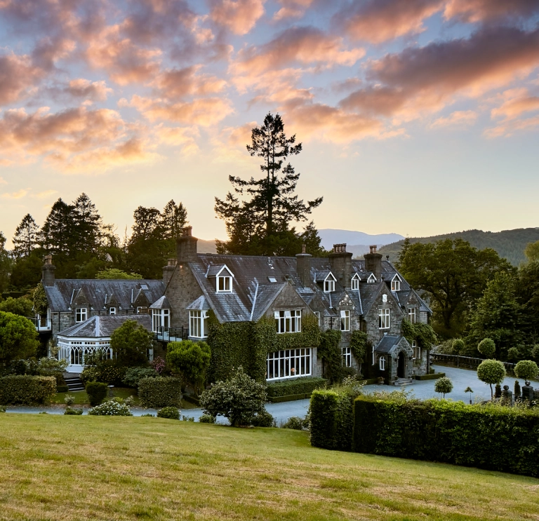 External shot of a hotel surrounded by greenery, under a dramatic sunset,