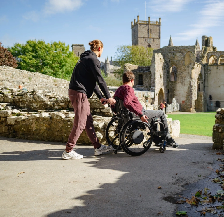Man in a wheelchair, along with his companion, looking around an historic site.