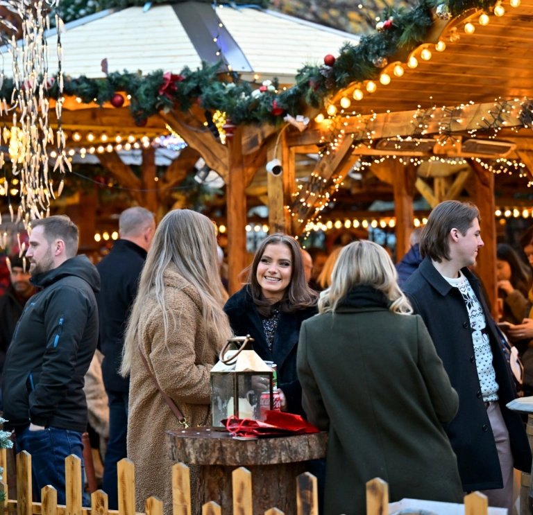 Group of ladies chatting and enjoying a drink at a Christmas market.
