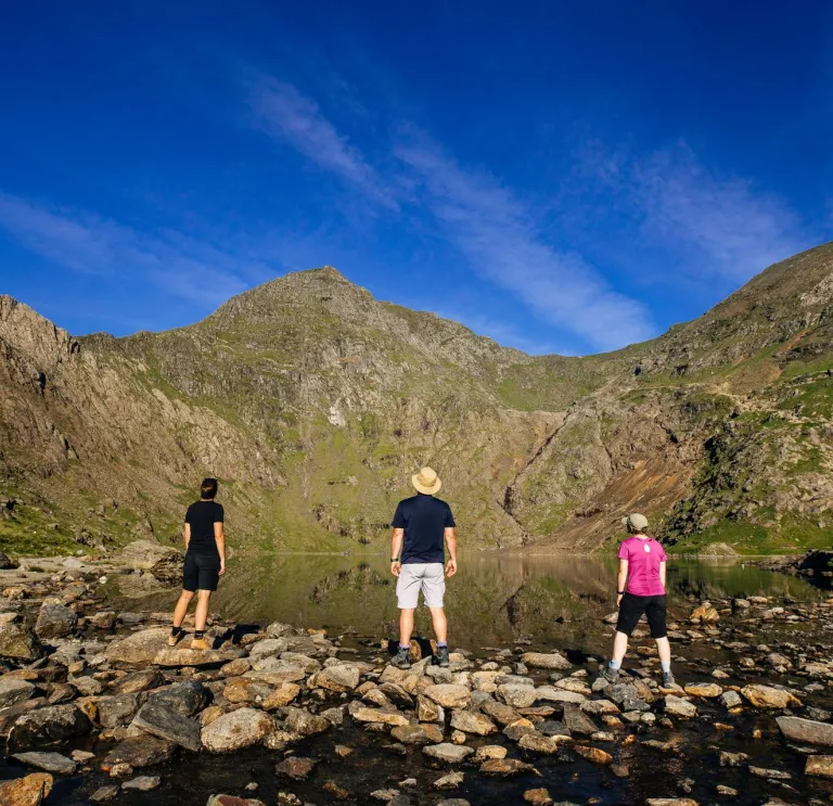People looking at a mountain by a lake.