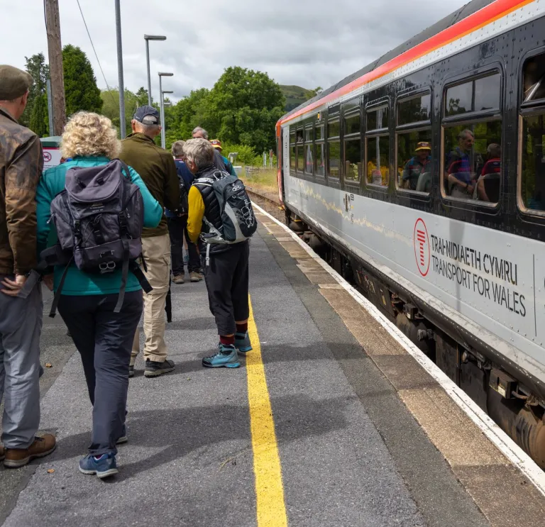 Walkers on a platform about to board a train.