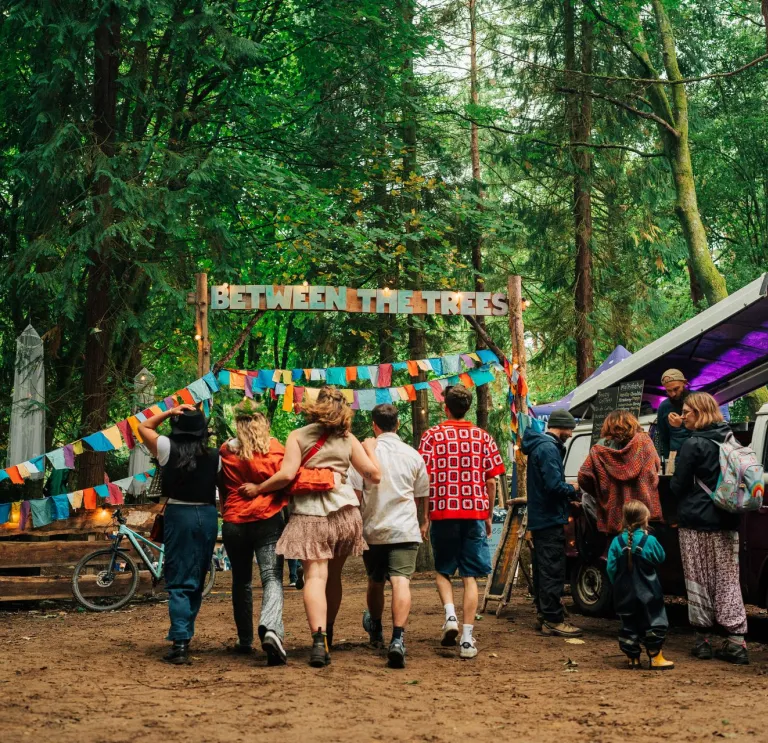 Group of people heading toward a festival in a forest.