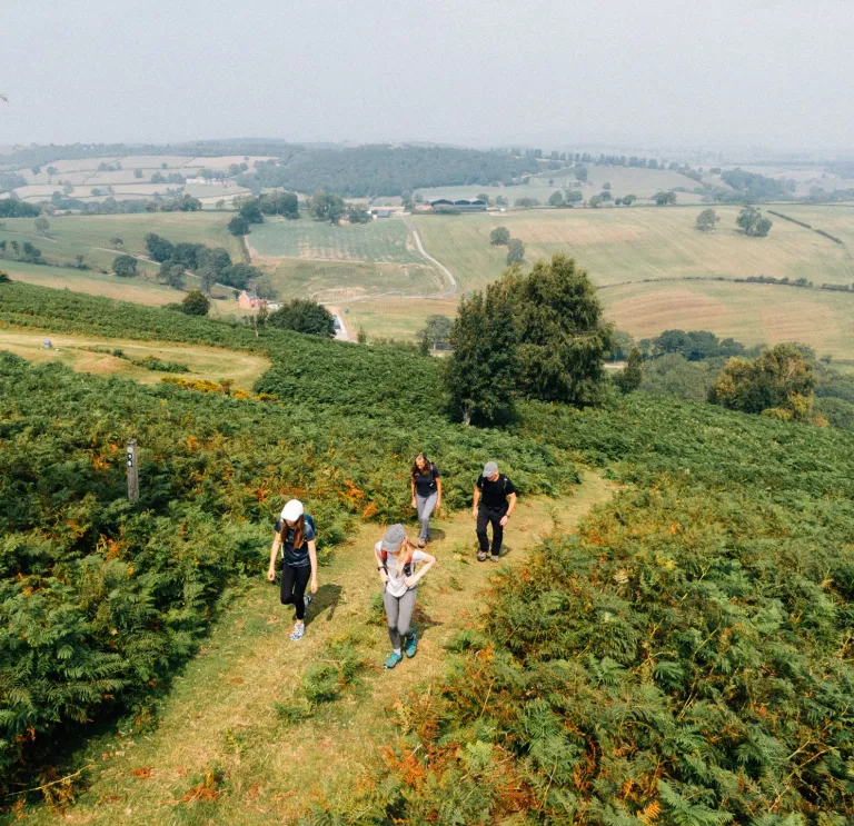 Group of walkers on a mountain footpath with scenic views beyond.