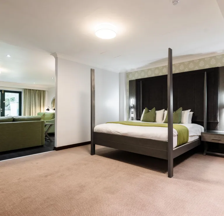 An executive bedroom in a hotel with a lounge and sliding doors to a terrace.