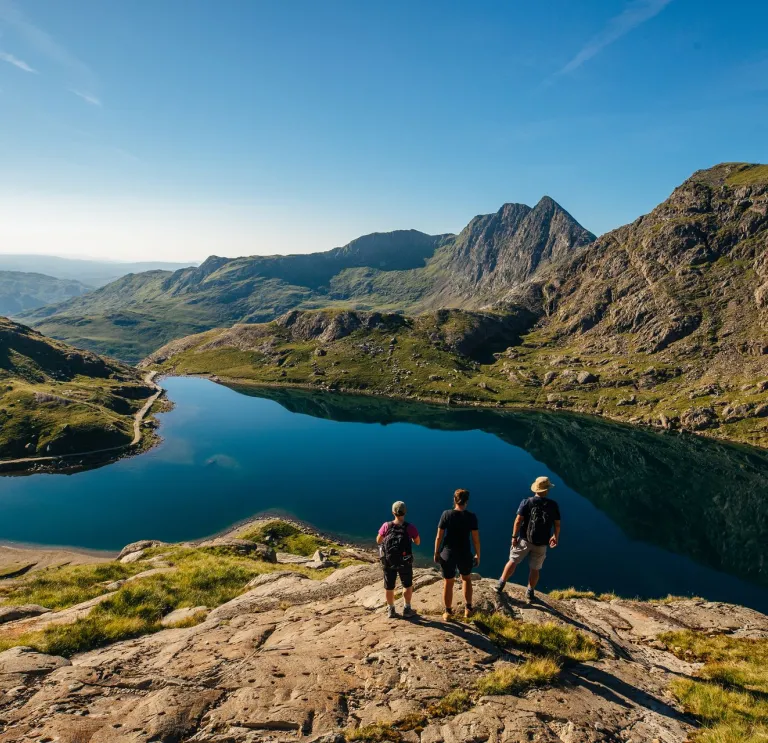 Group of walkers overlooking a lake on the top of a mountain.