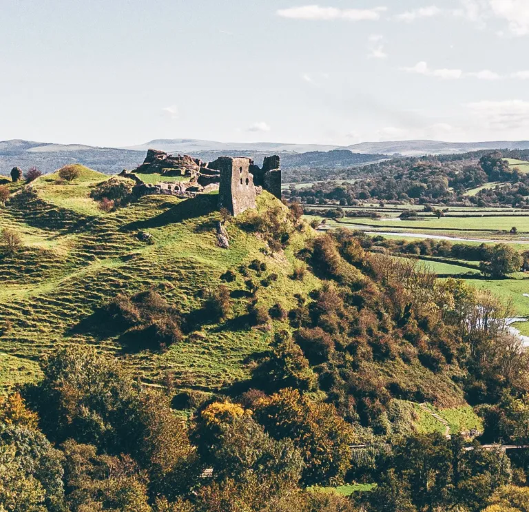 A castle on a hill with views alongside a river surrounded by countryside.