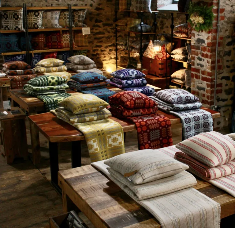 Woven blankets and cushions on display in a shop.
