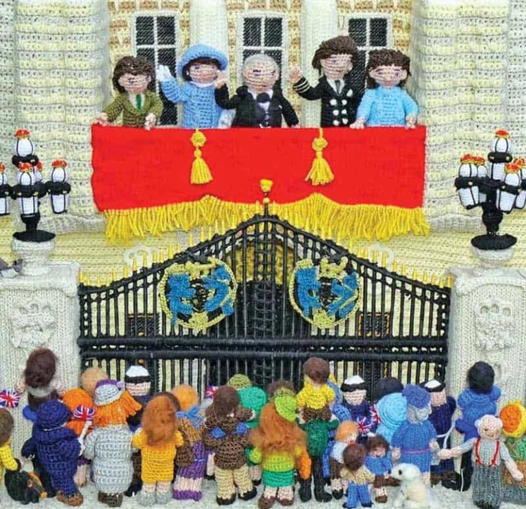 Knitted scene of the Royal Family on a balcony waving to crowds below.
