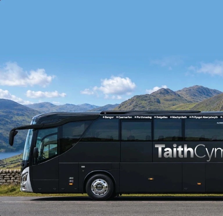 A coach parked up with views of mountains and a lake beyond.
