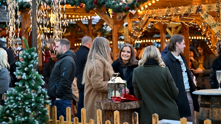 Group of ladies chatting and enjoying a drink at a Christmas market.