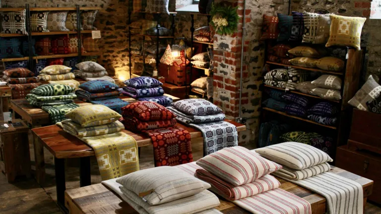 Woven blankets and cushions on display in a shop.