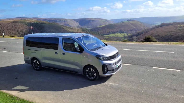 Minibus parked on an open road with a backdrop of spectacular mountains.