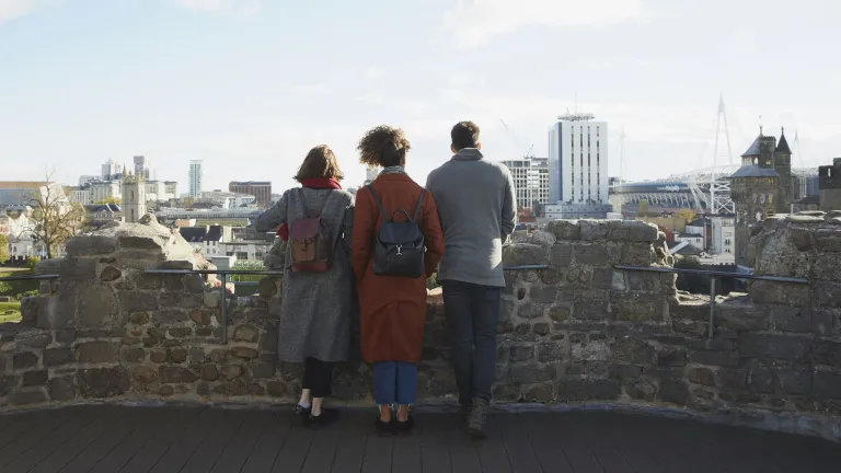 Group of people on a castle turret looking out towards the city.