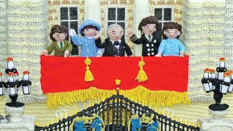 Knitted scene of the Royal Family on a balcony waving to crowds below.