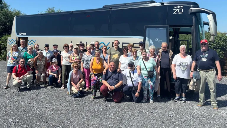 Group of people standing by a coach smiling at the camera