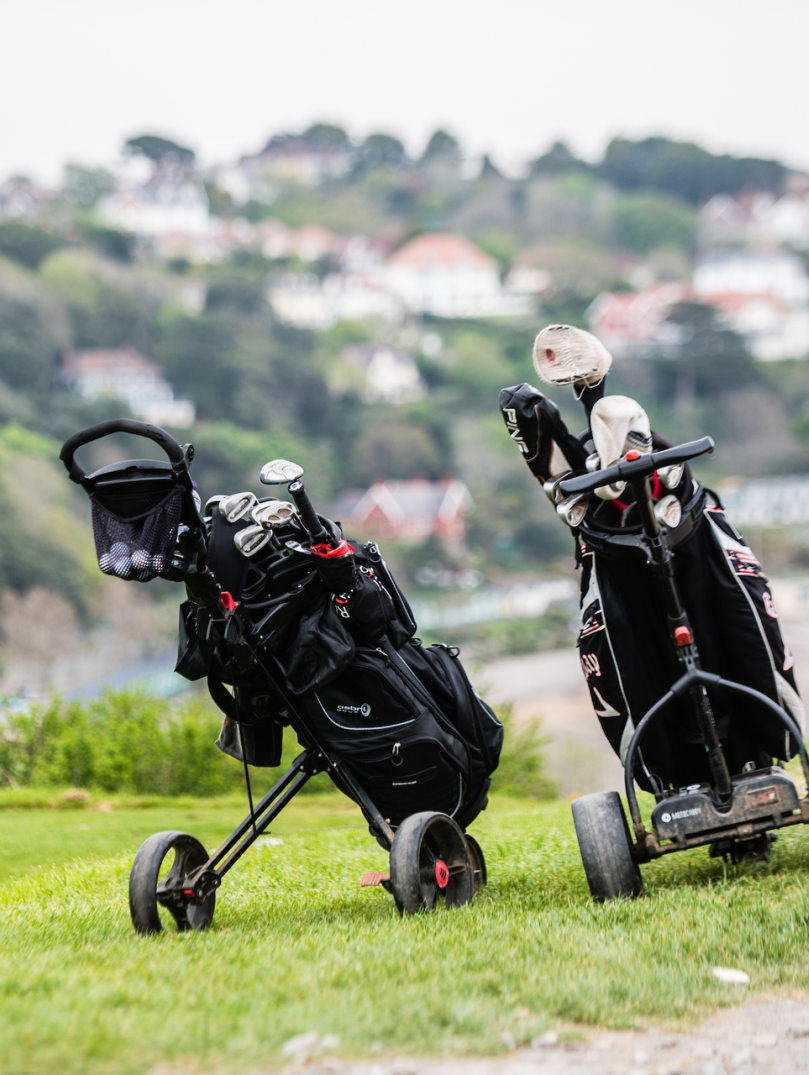 Golfing trolleys with Langland Bay in the background.