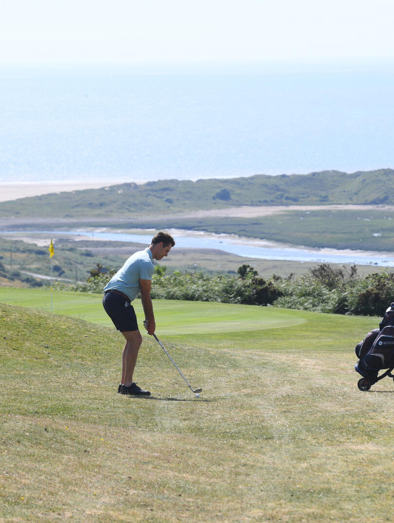 Golfer preparing to chip the ball onto the green at Southerndown Golf Club.