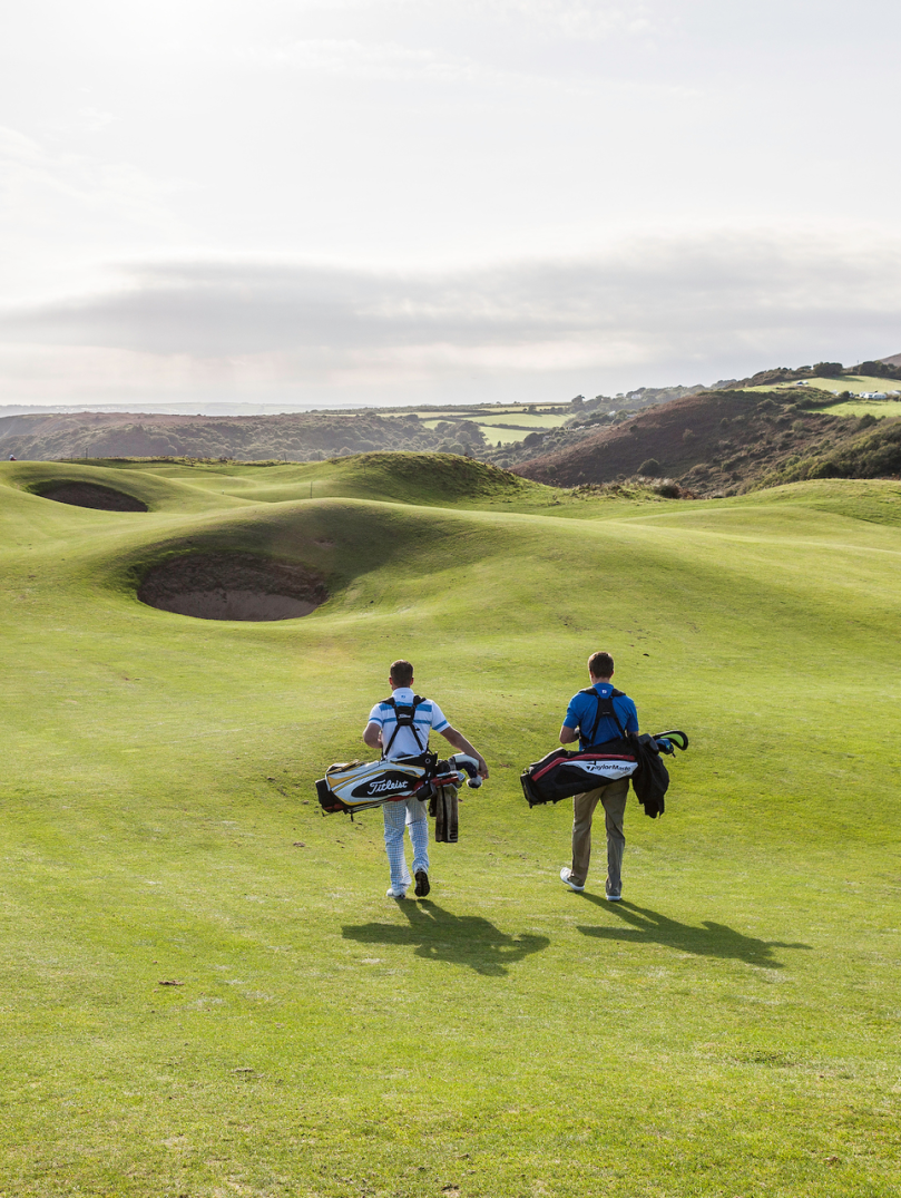 Golfers walking to the next tee with views of the coastline.