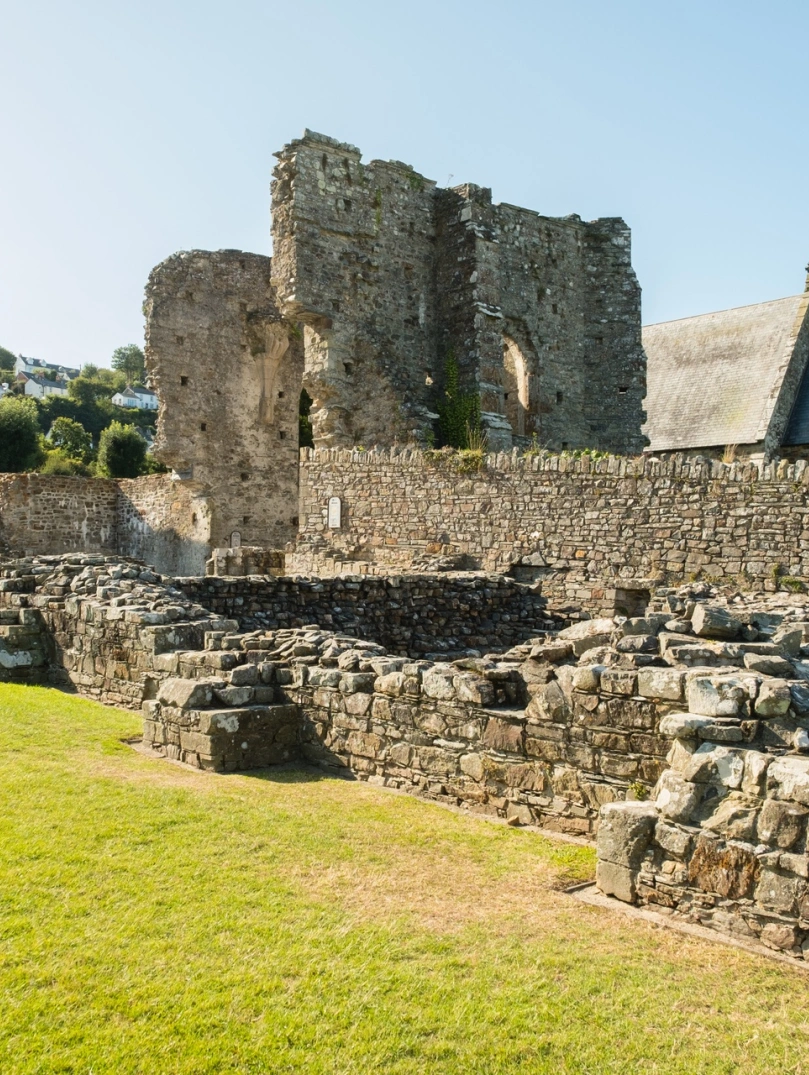 The ruins of an abbey with a church in the background.