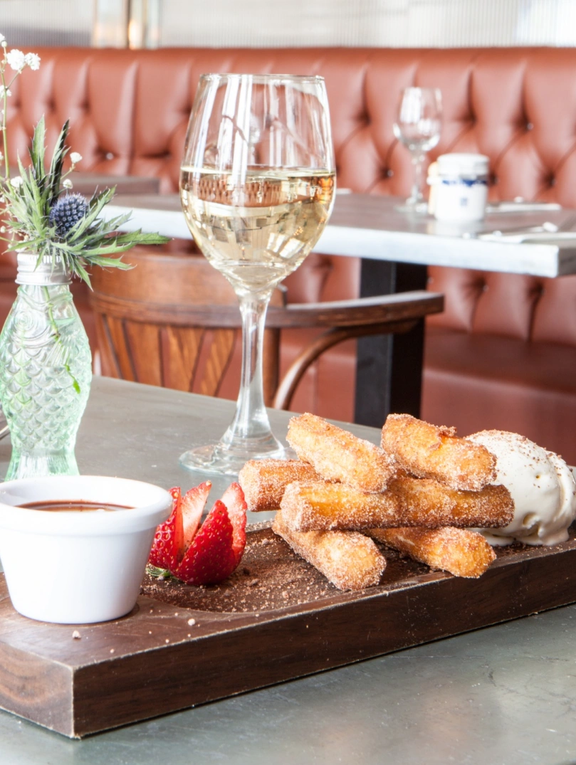 Desserts and wine on a table in a restaurant.