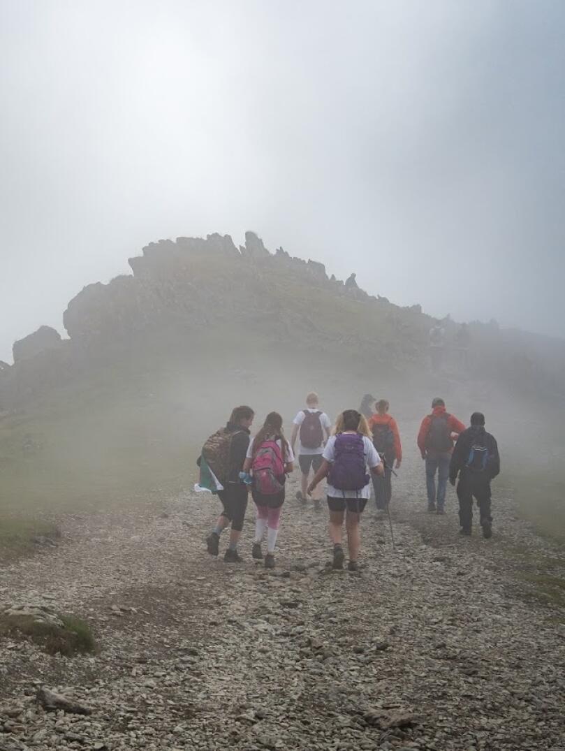 Clients walking along a mountain path amongst clouds.